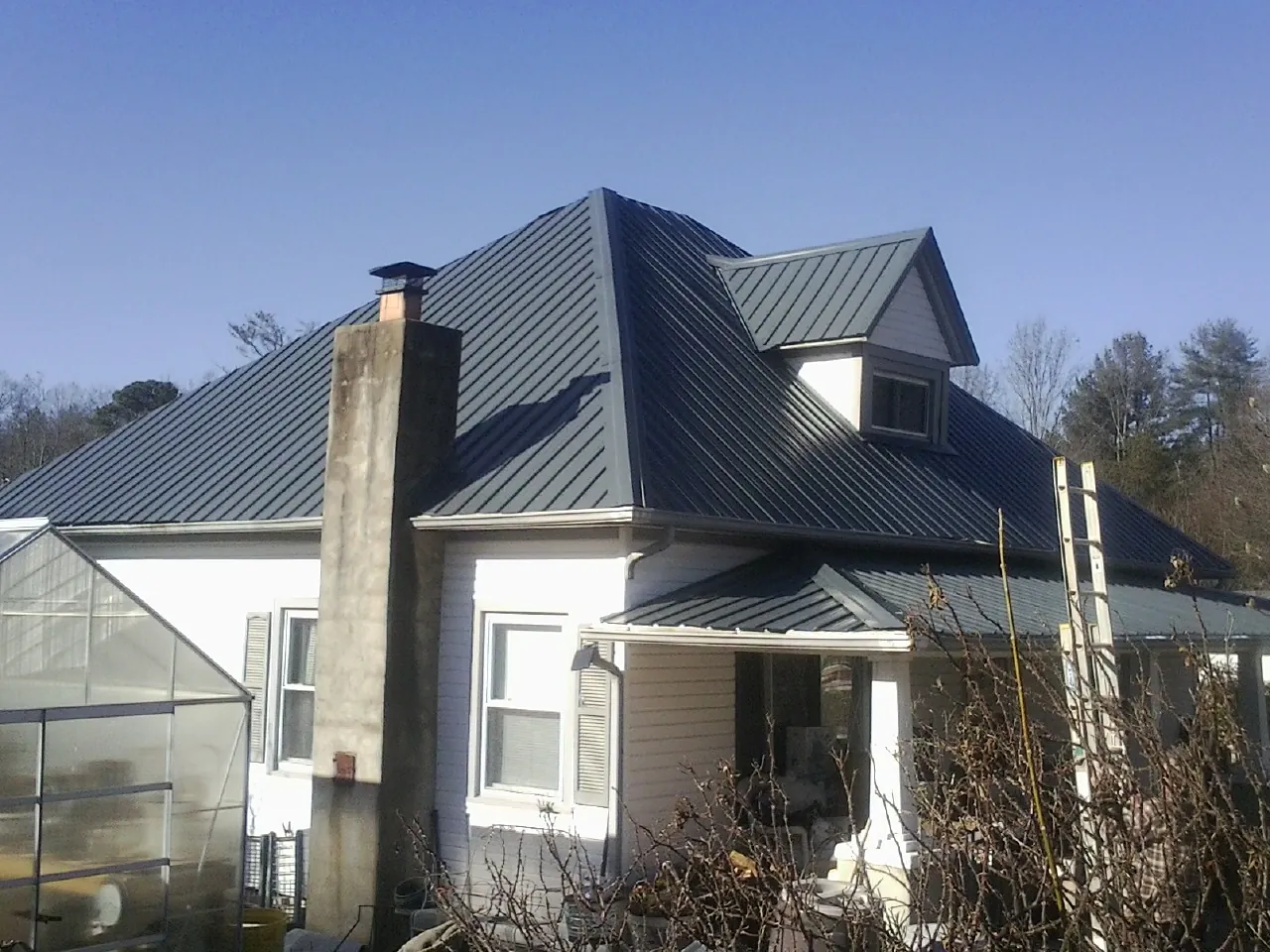 Dark blue standing seam metal roof on a white farmhouse with dormer — Slate & Tile Roof Repair by Roofing Brothers in Old Town