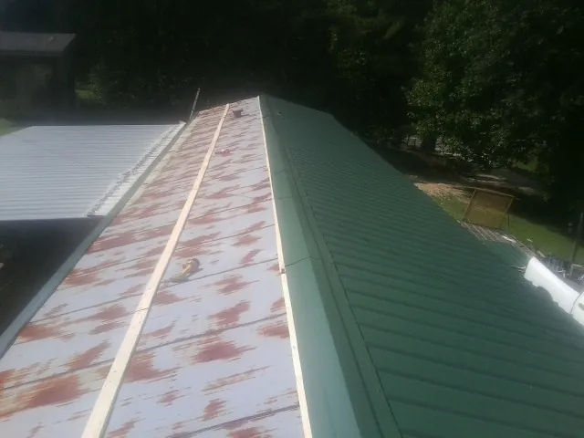 Old rusted panels beside newly installed green metal roofing — Wind Damage Roof Repair by Roofing Brothers in Old Town