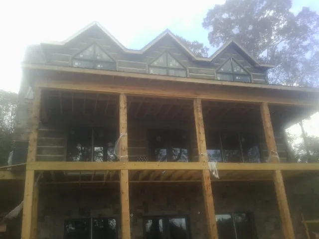 Dormers and porch framing on a large log home under construction — Roof Coating work by our crew in Old Town