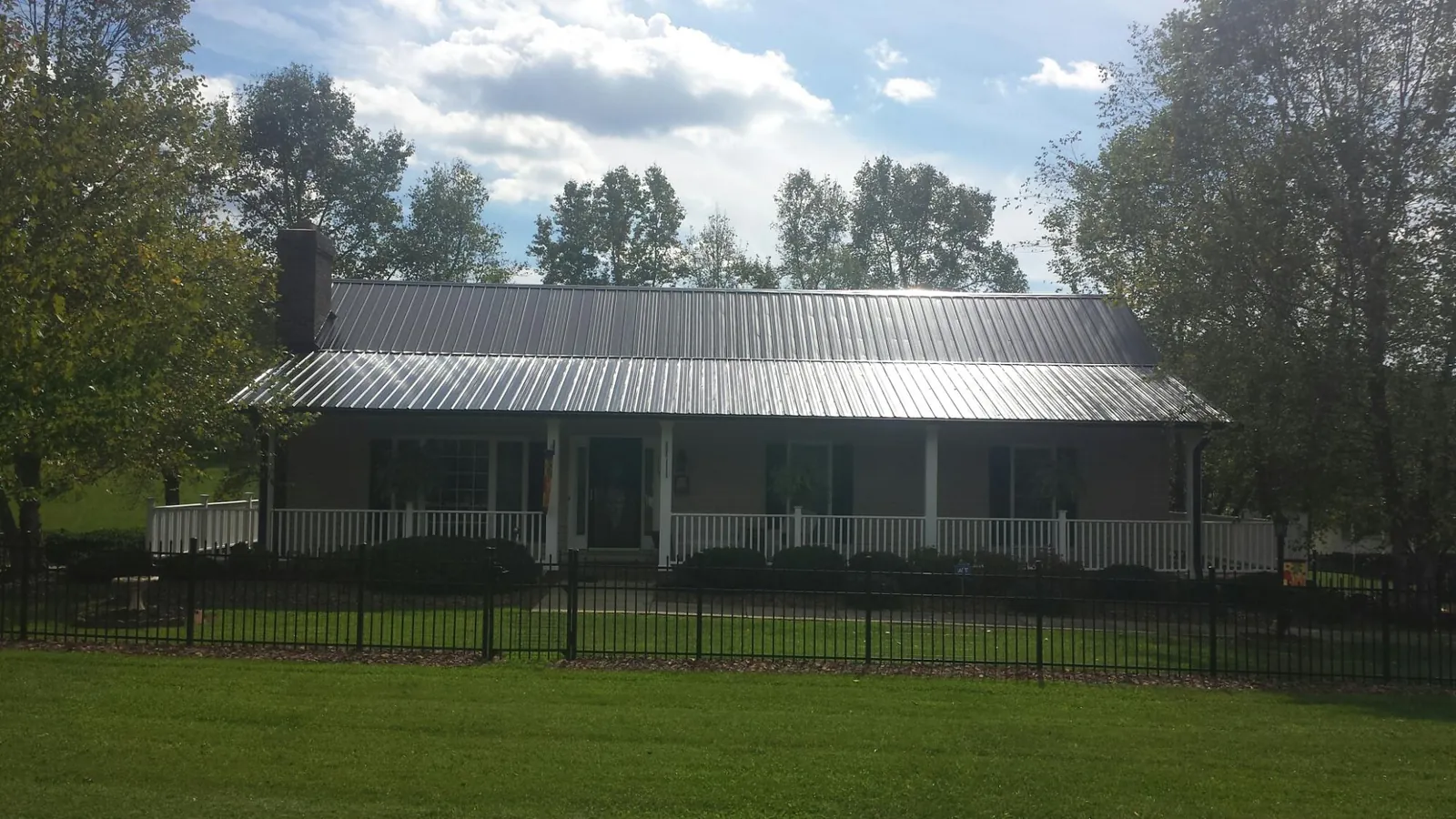 Gray metal roof on a brick ranch with a full width front porch — Gutter Guard Installation work by our crew in Old Town