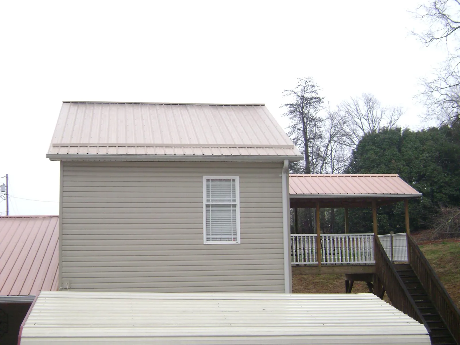 Tan metal roofs on a two story addition and attached porch, from a Roof Replacement job in Old Town