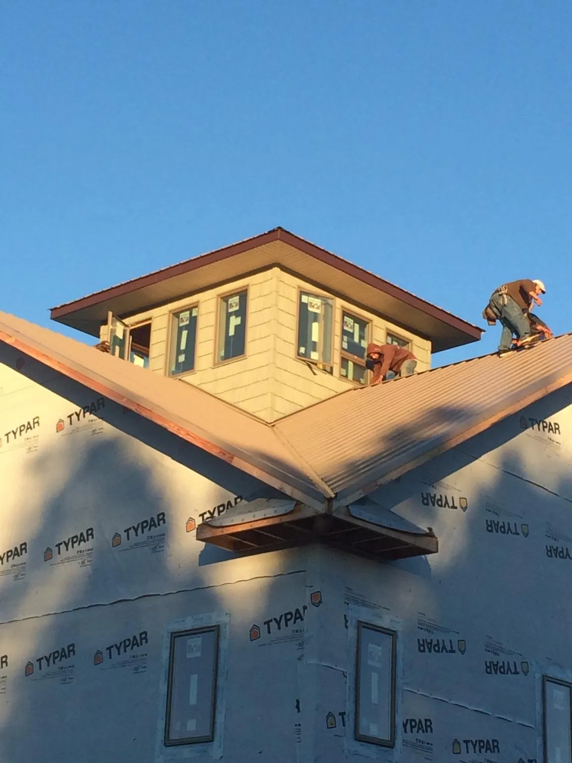 Roofers working around a rooftop cupola on a new metal roof at sunset — Roof Waterproofing in Old Town by Roofing Brothers